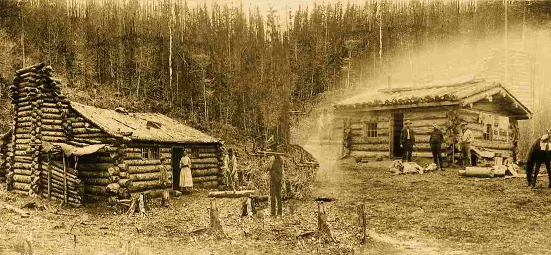 Sepia photograph of pioneer log cabins in a forest clearing in the Old West