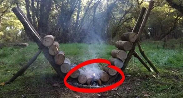 Self-feeding log fire built with two slanted log racks that roll new wood into the flames
